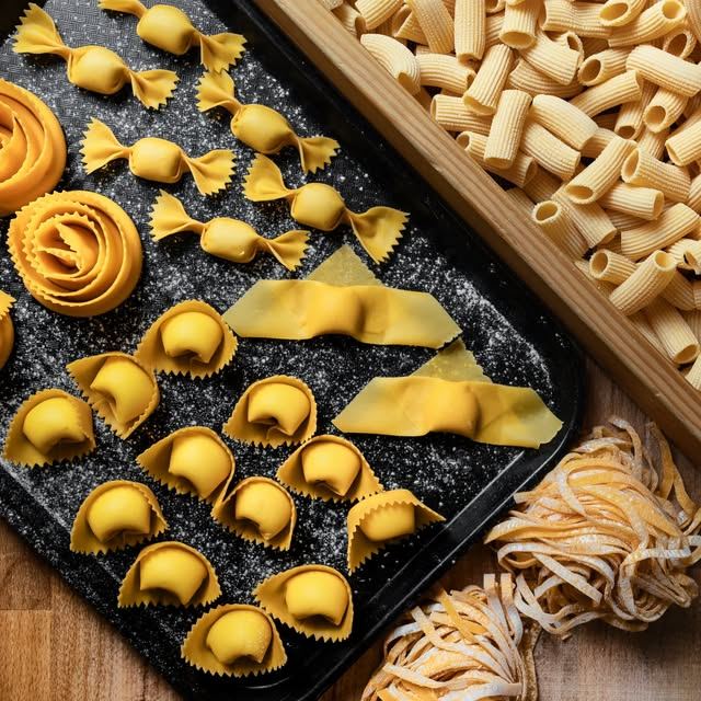 Tray of freshly made pasta shapes: farfalle, cappelletti, rigatoni and tagliatelle